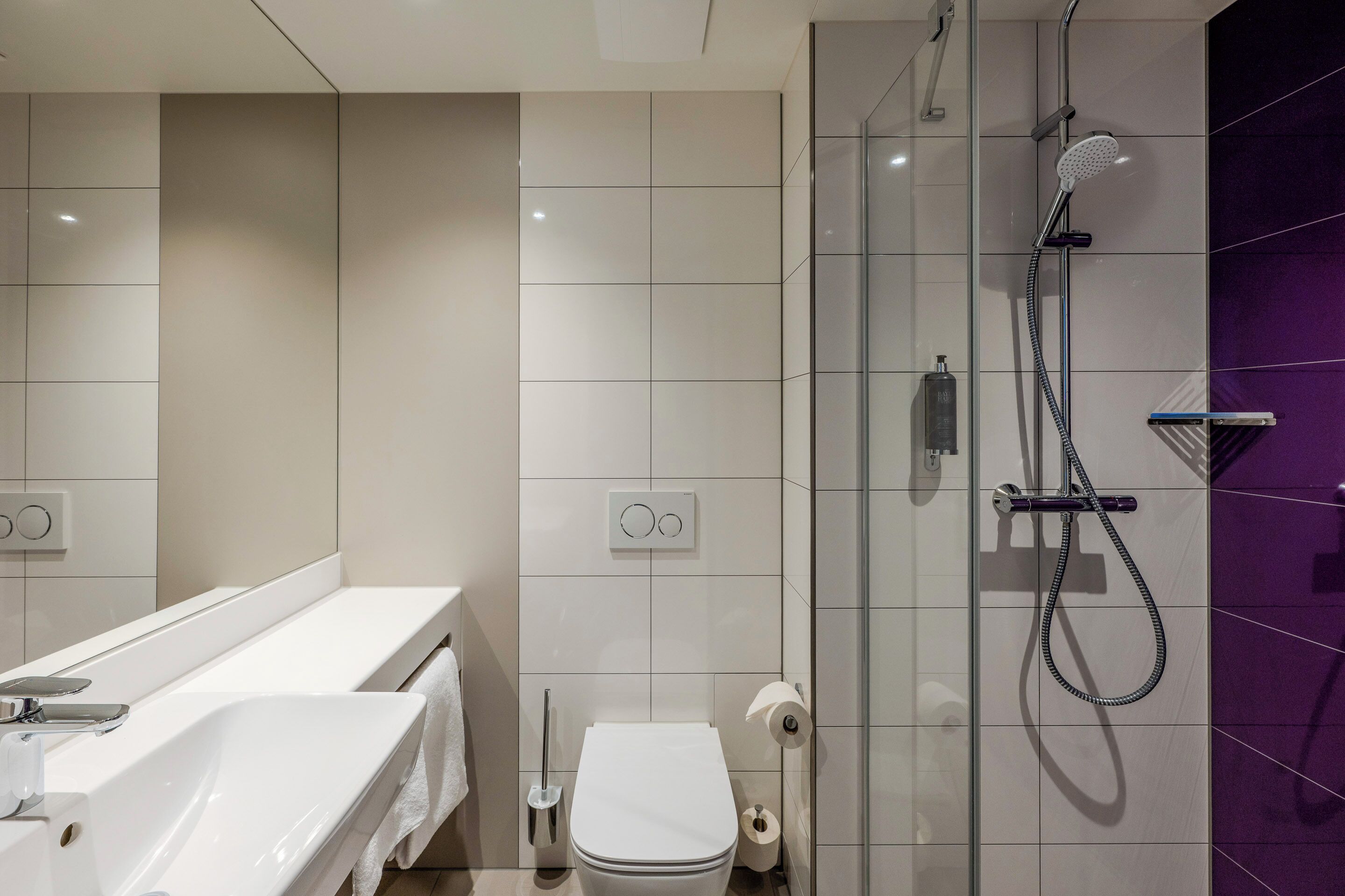 Un baño moderno con lavamanos, inodoro y ducha blancos.