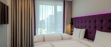Habitación de hotel con una cama grande, televisión y vistas de la ciudad a través de la ventana.