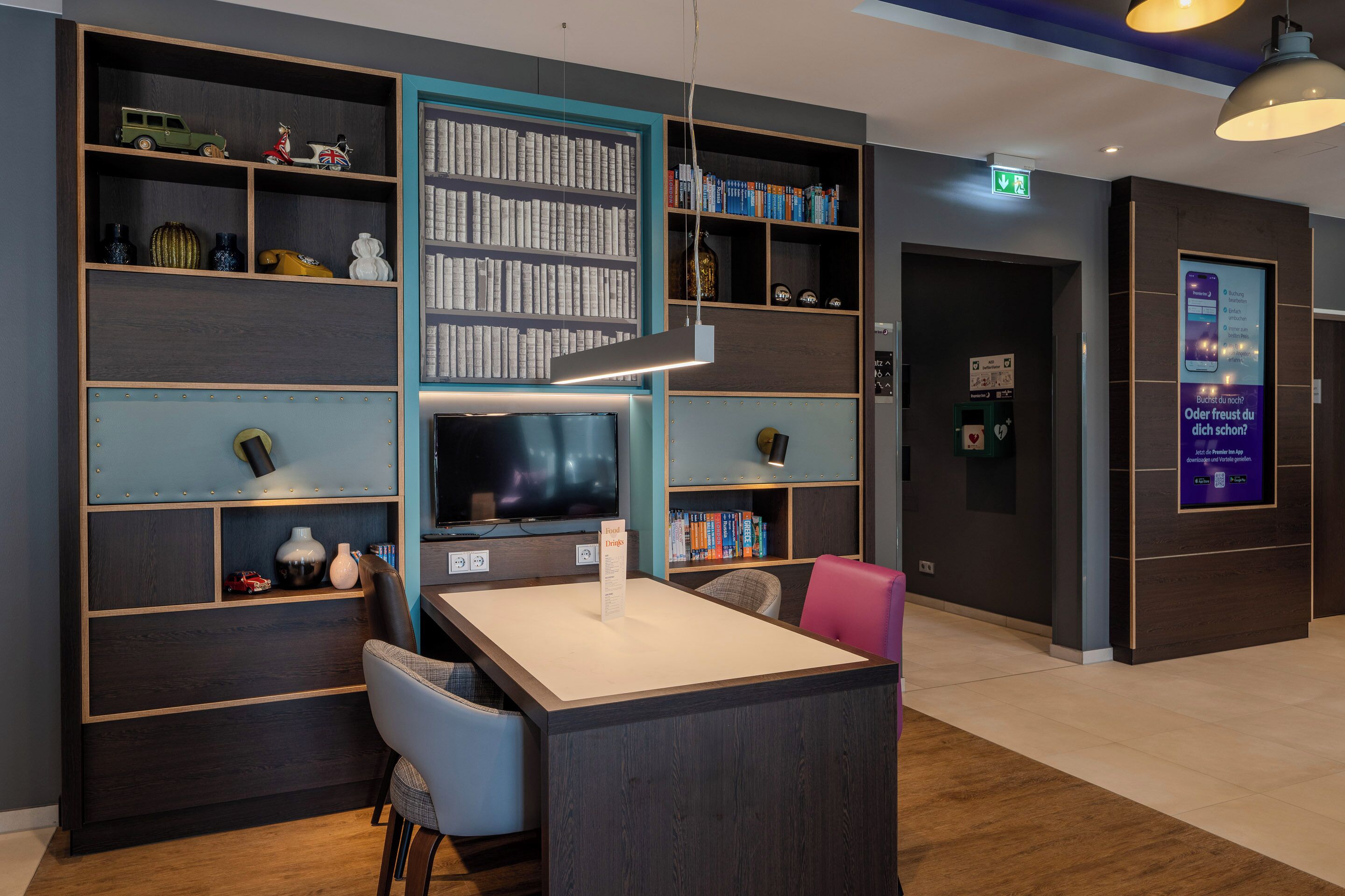 A modern library with bookshelves, a television, and a reception desk.
