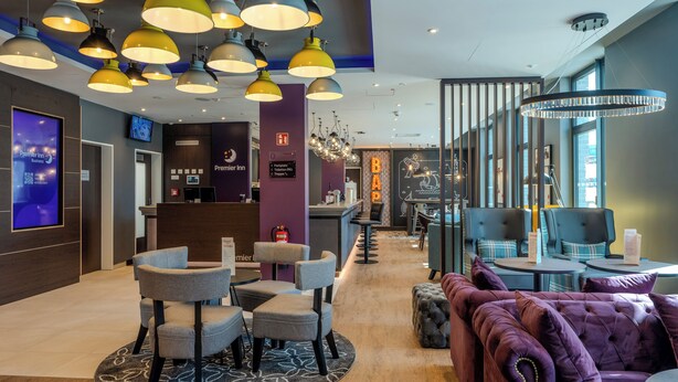 A hotel lobby with multiple seating areas, a reception desk, and a bar.