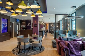 A hotel lobby with multiple seating areas, a reception desk, and a bar. - Premier Inn Bremerhaven (Bremen)