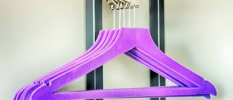 A purple hanger with a zipper, hanging on a metal rod.