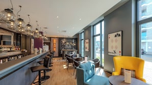 A bar area with stools, a counter, and hanging light fixtures.
