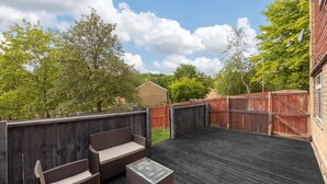 Een terras buiten met een houten omheining, een bank en een tafel.