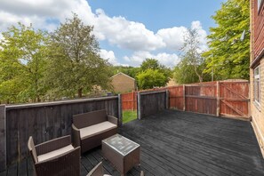 Eine Terrasse im Freien mit Holzzaun, einer Bank und einem Tisch.