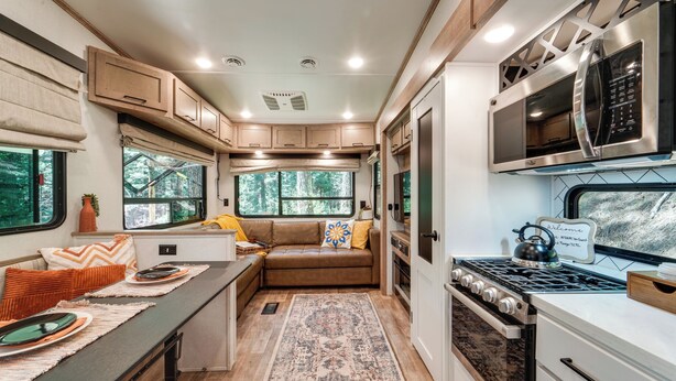 A compact RV kitchen with a stove, microwave, and seating area. - Wooded Getaway w/ Beautiful Views in Nevada City! (Nevada City)