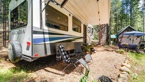 A recreational vehicle with a covered dining area, a small cabin, and outdoor seating. - Wooded Getaway w/ Beautiful Views in Nevada City! (Nevada City)