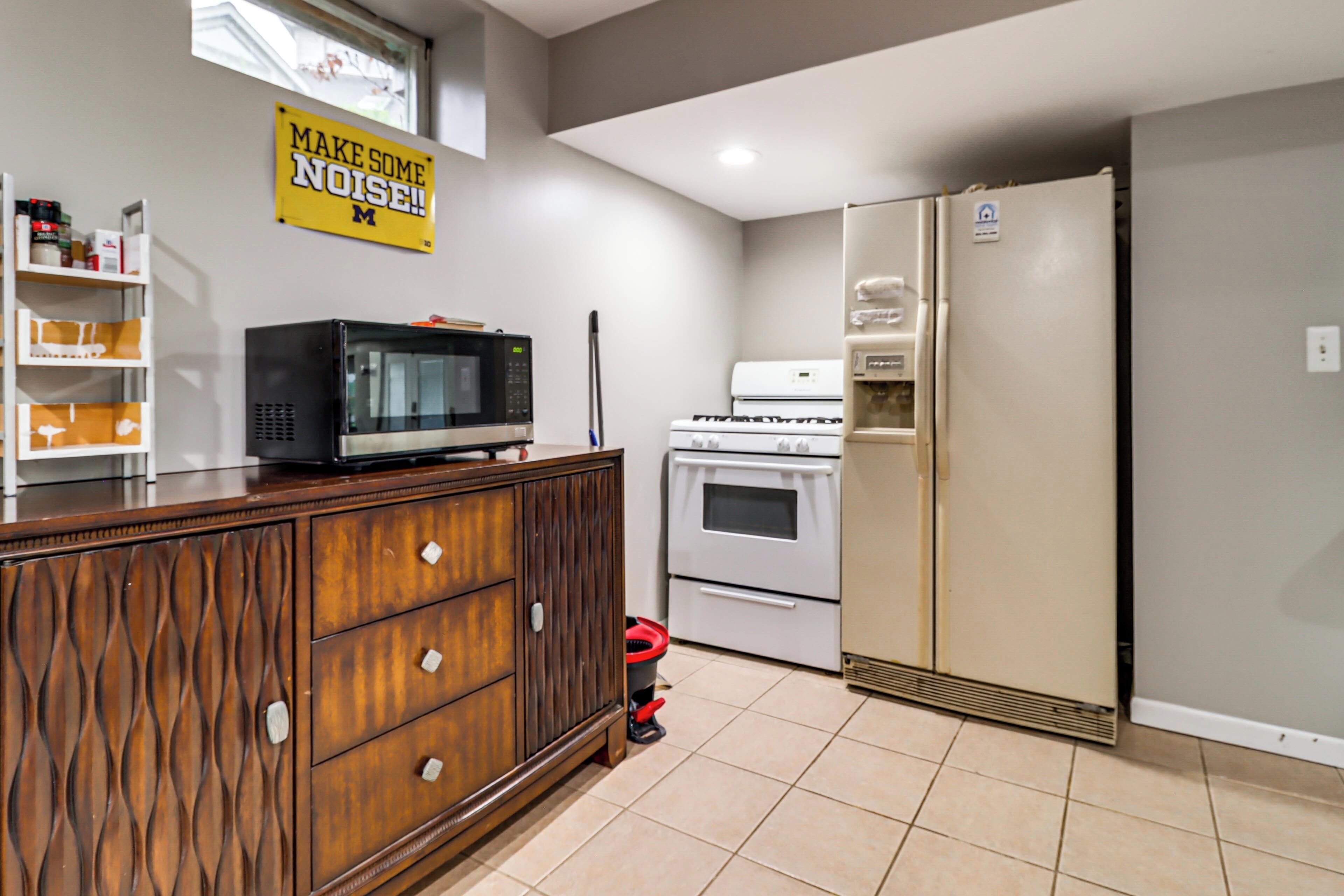 A kitchen with a microwave, oven, refrigerator, and a cabinet with drawers.