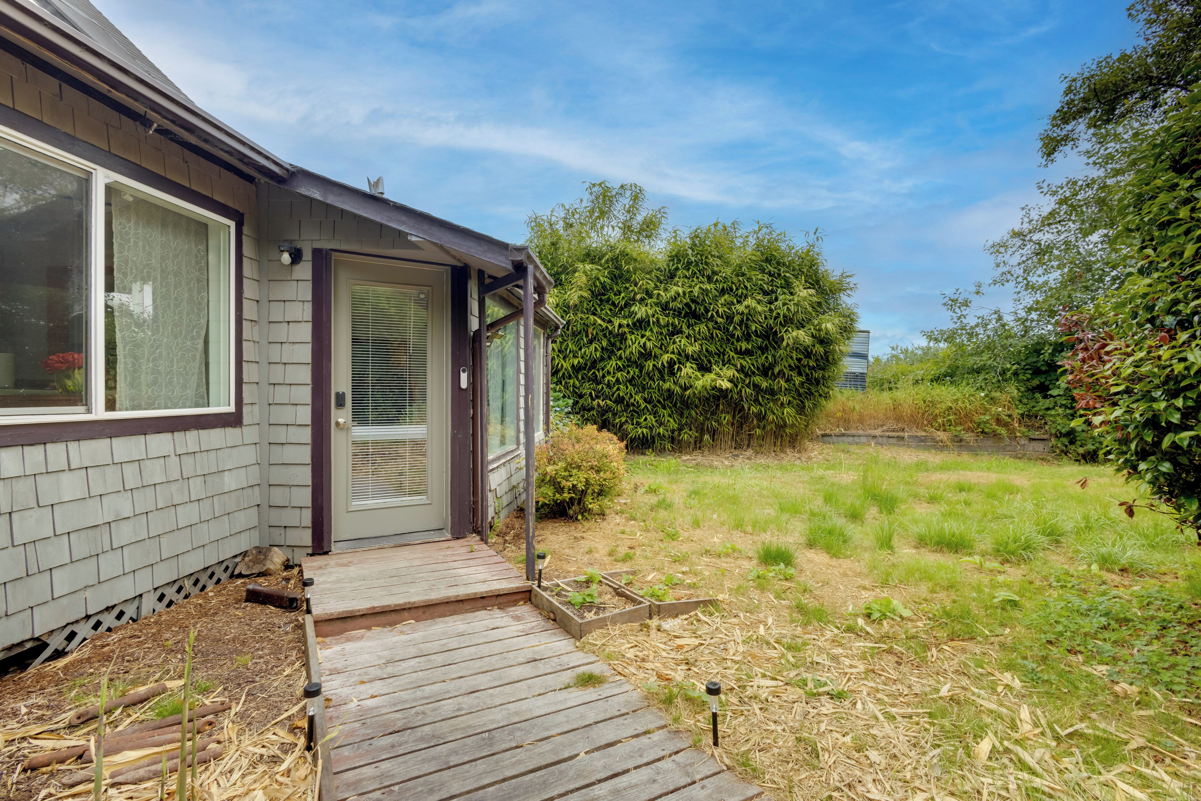 A house with a wooden deck, a door, and a window with a curtain.
