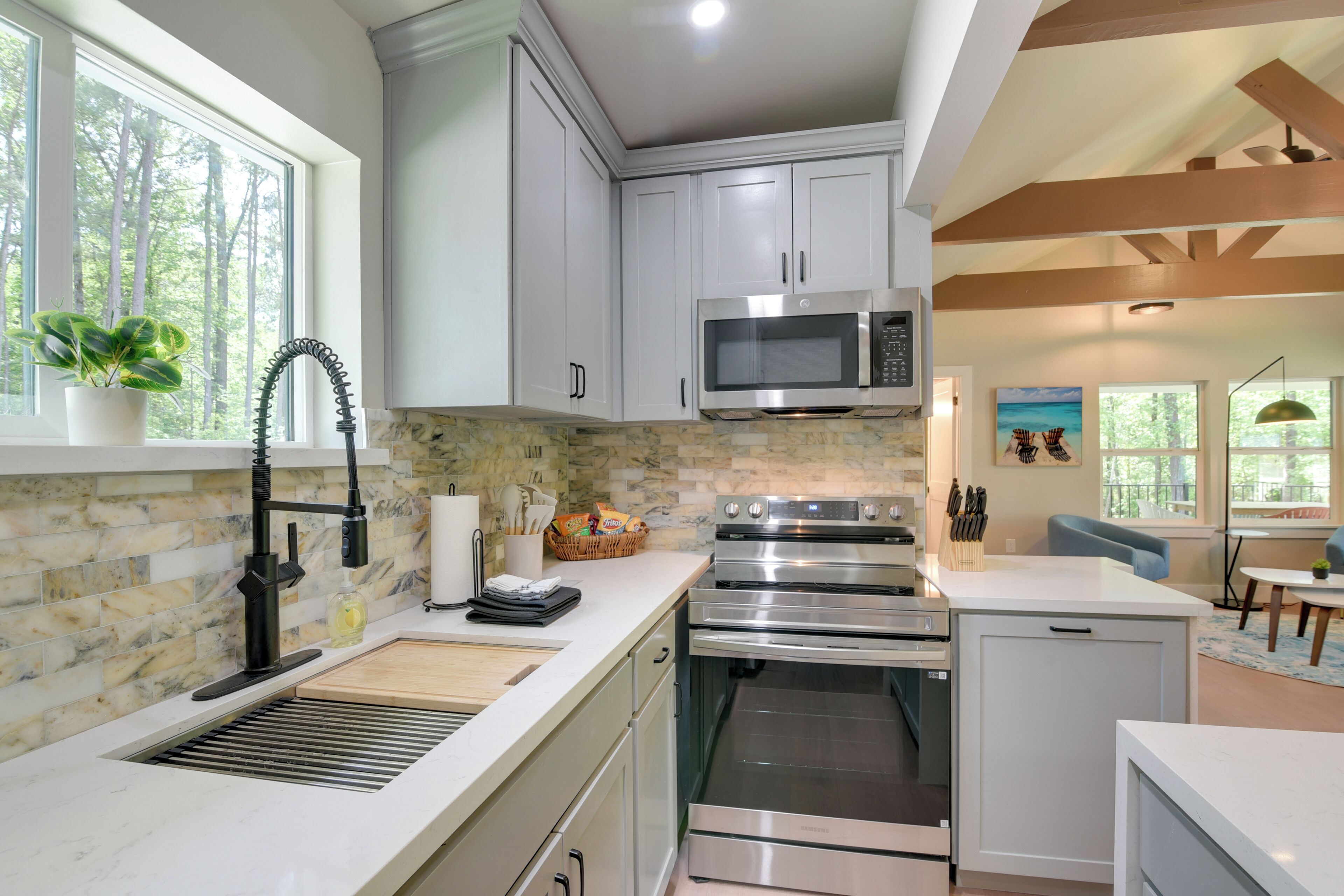 A modern kitchen with white cabinets, a stainless steel microwave, and an oven.