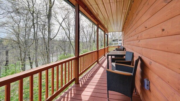 A wooden deck with a railing, a table with chairs, and a view of trees. - 2 Cabins Near Lake Cumberland Boat Ramps! (Somerset)