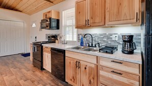 A kitchen with wooden cabinets, a stainless steel refrigerator, a coffee maker, and a dishwasher. - 2 Cabins Near Lake Cumberland Boat Ramps! (Somerset)