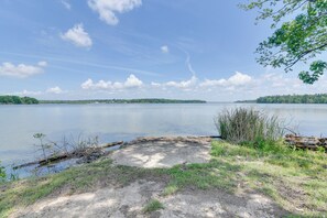 A lakeside view with a clear sky, calm water, and a grassy area with trees. - Angler's Escape on Lake Livingston w/ Private Dock (Pointblank)