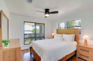 Quarto com cama, mesas de cabeceira, ventilador de teto e janelas amplas.