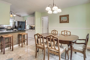 A dining area with a wooden table and chairs, a kitchen in the background, and a ceiling fan. - Screened Porch, Private Pool! Family Home in Aiken (Aiken)