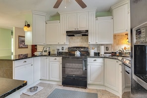 A kitchen with white cabinets, a black stove, and a tiled backsplash. - Screened Porch, Private Pool! Family Home in Aiken (Aiken)