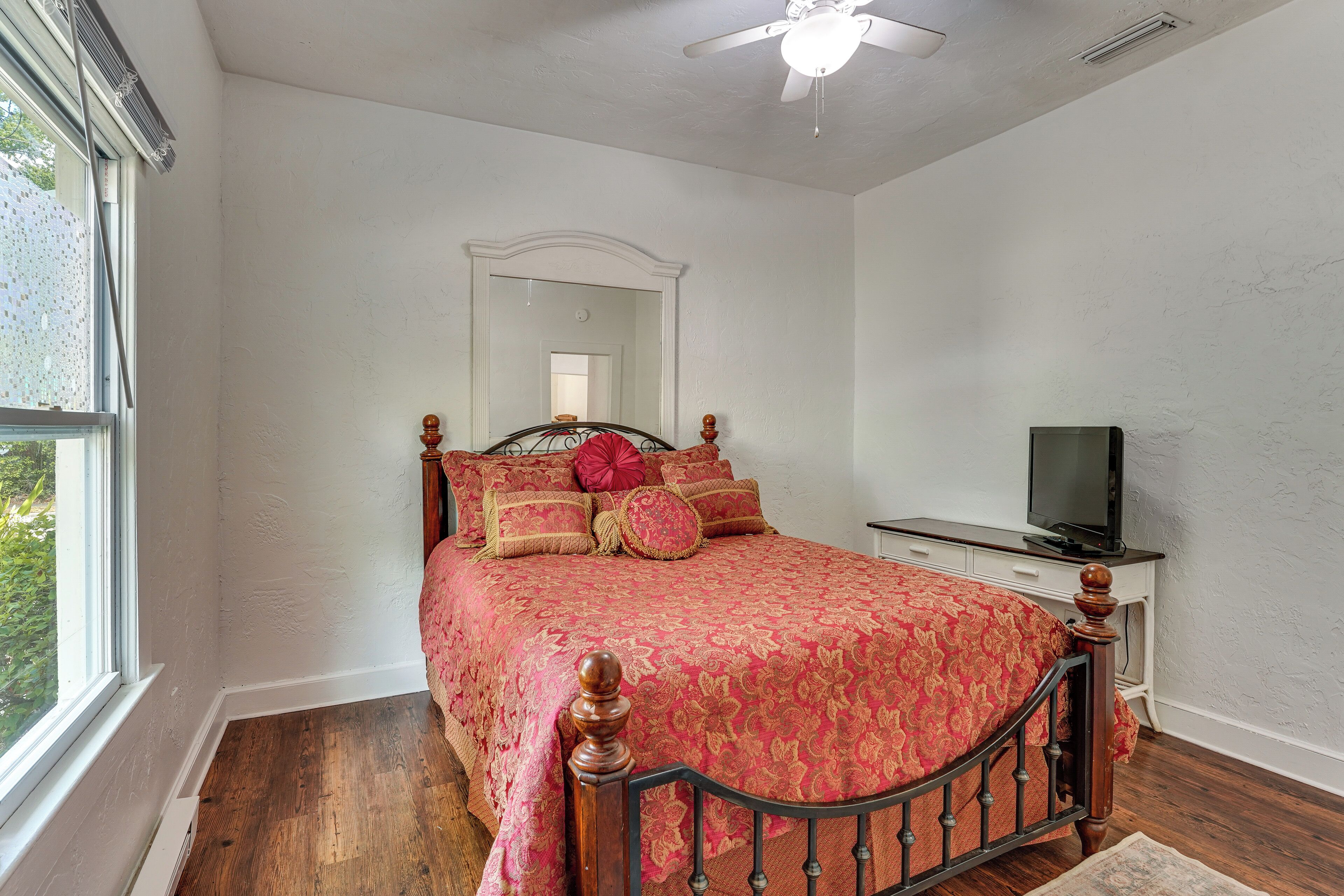 A bedroom with a wooden bed, a television, and a window.