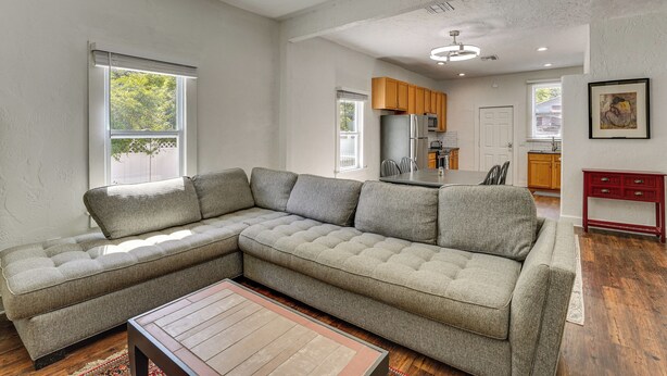 A modern living room with a sectional sofa, a coffee table, and a kitchen in the background.