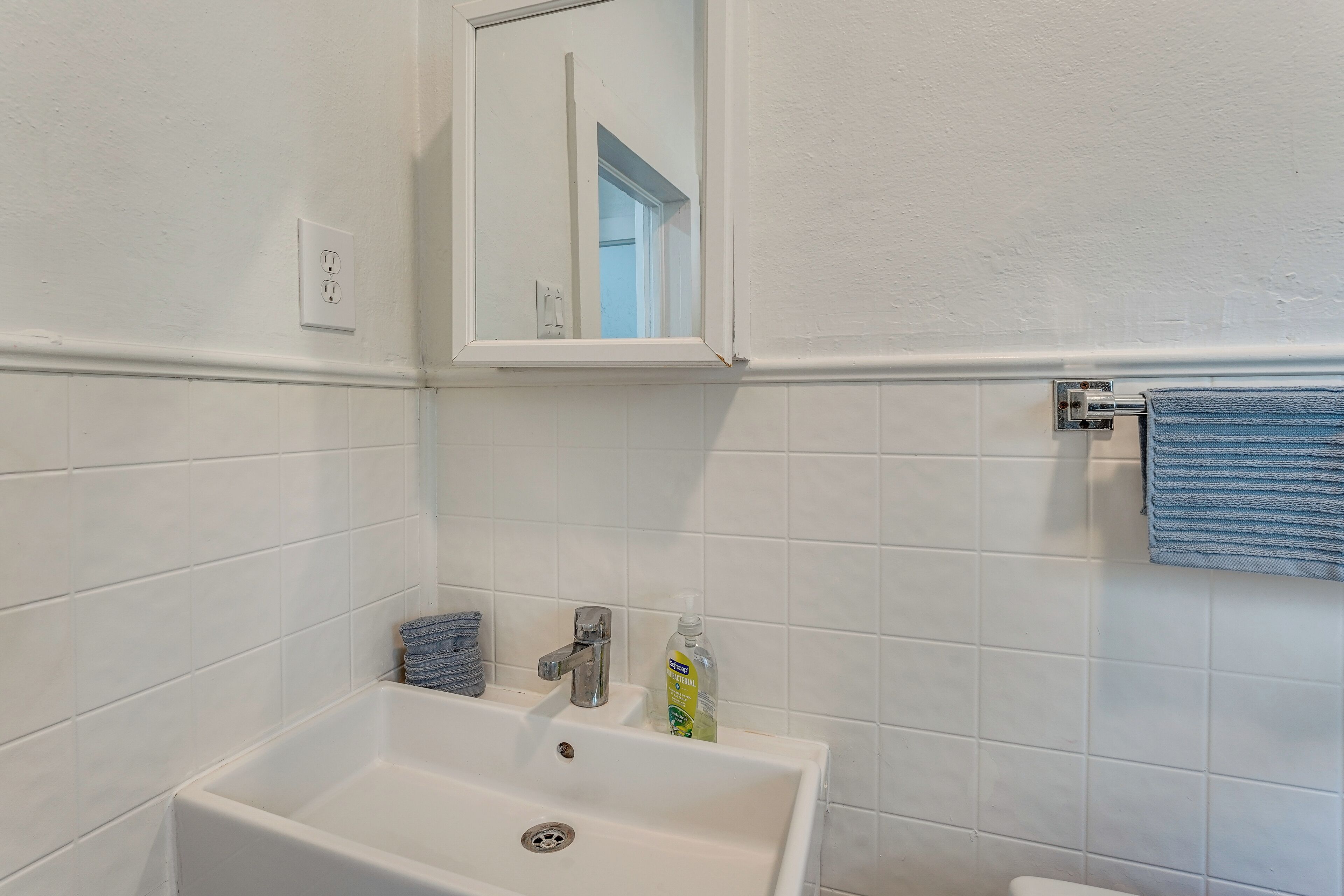 Une salle de bain avec un lavabo blanc, un miroir, un porte-serviettes et des toilettes.