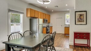 A modern kitchen with wooden cabinets, a stainless steel refrigerator, a microwave, and a dining area with a table and chairs.