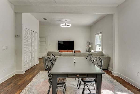 A dining area with a table, chairs, a sofa, and a television.