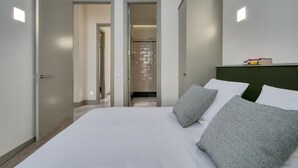 Ein Hotelzimmer mit einem großen Bett, zwei Türen, einer Dusche und einem kleinen Tisch mit Büchern.