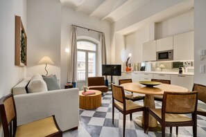 Ein modernes Wohnzimmer mit einer Couch, einem Esstisch, Stühlen und einem Fernseher.