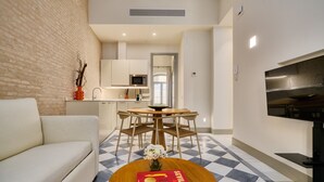 A modern living room with a sofa, a dining table with chairs, a book, and a TV. - Luis de Vargas 1.1 by Home at Homes (Seville)