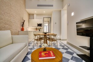 Ein modernes Wohnzimmer mit einer Couch, einem Esstisch mit Stühlen, einem Buch und einem Fernseher.