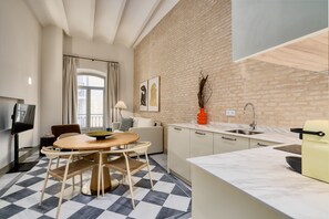 Una cucina moderna con una parete in mattoni, un'area pranzo con pavimento a scacchi e un divano.