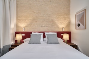 Ein Hotelzimmer mit Bett, zwei Nachttischlampen, einem Kopfteil und einem Wandbild.