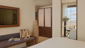 Habitación de hotel con cama, sofá, espejo, ventana con vistas y una mesita con una planta.