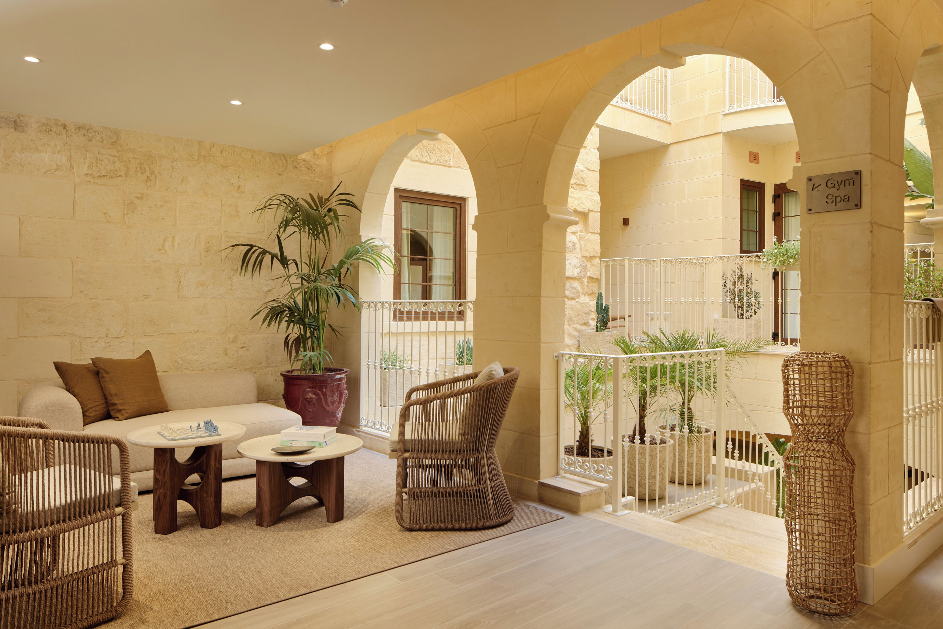 A cozy indoor seating area with a sofa, two wicker chairs, a coffee table, and a potted plant.