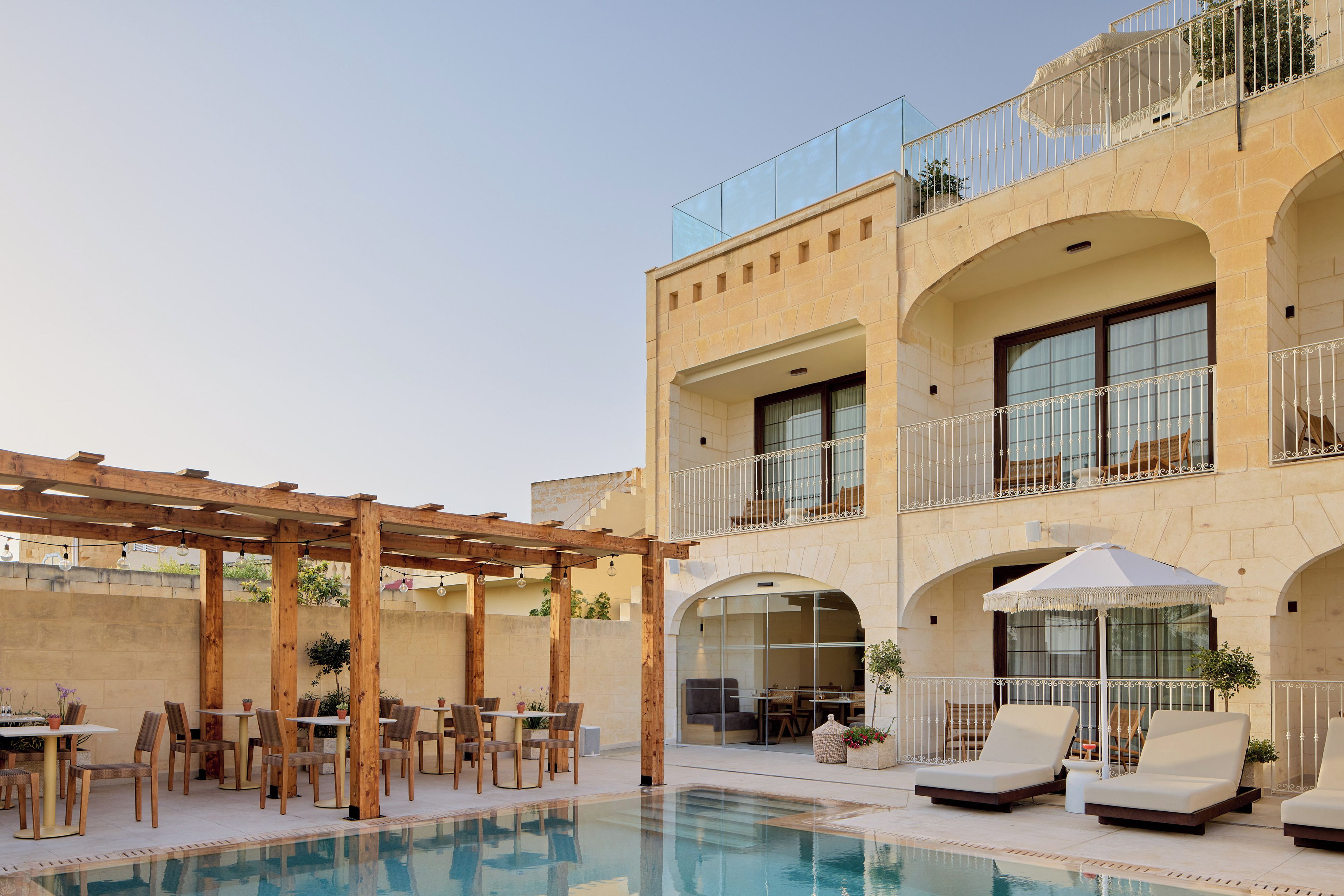 A poolside area with outdoor seating and a pergola.