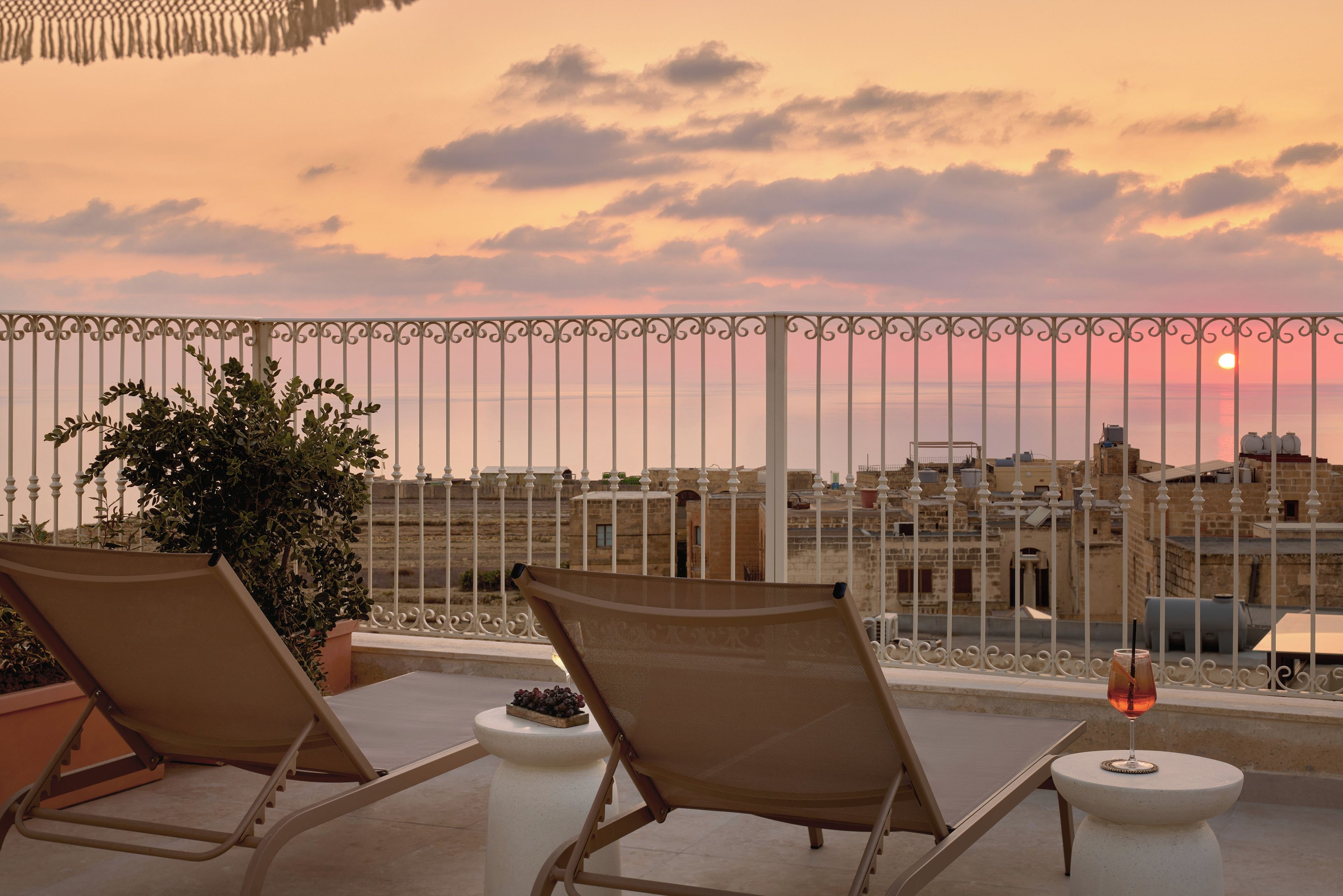 A balcony with two lounge chairs, a small table, and a potted plant.