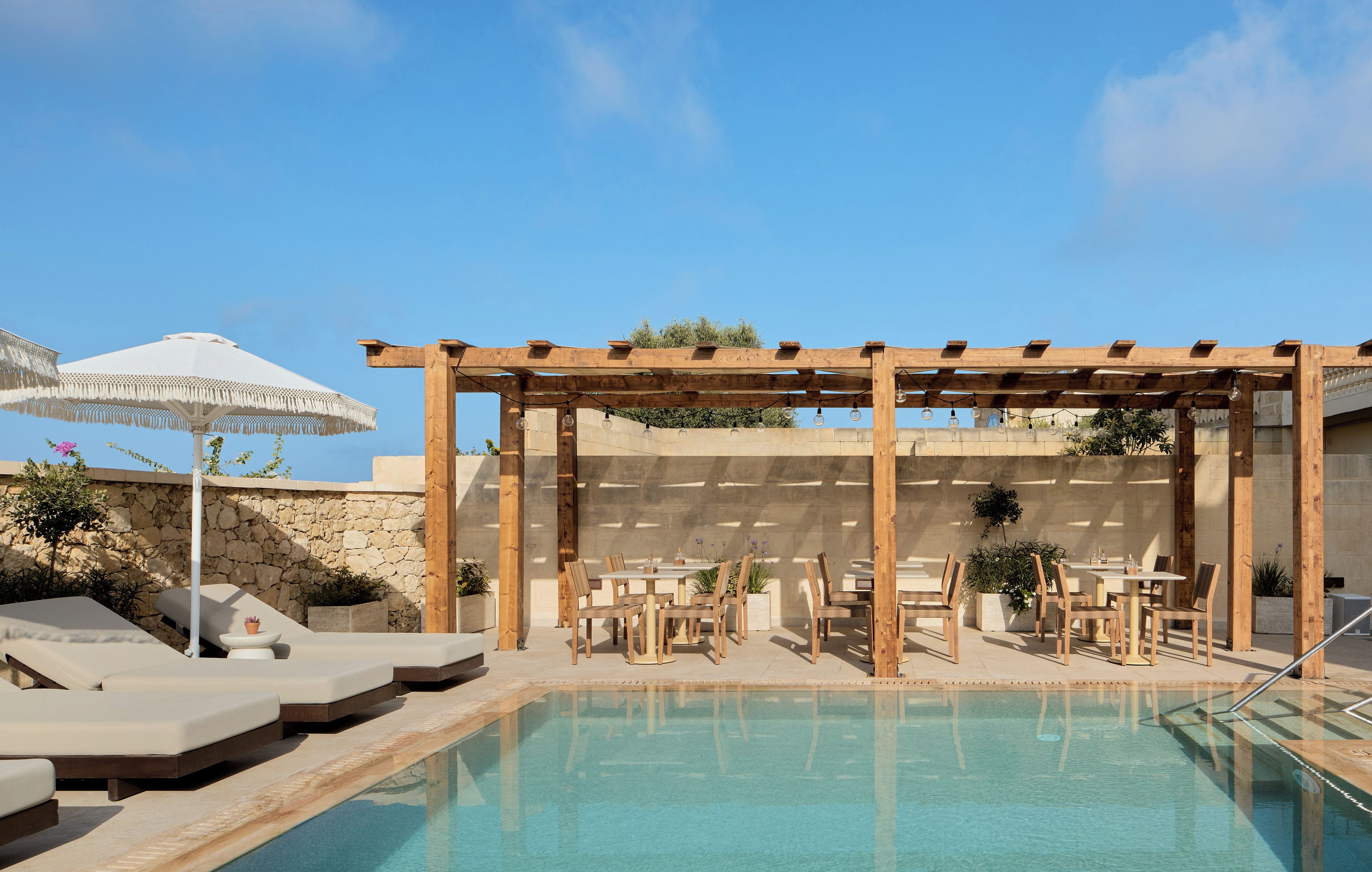 A pool area with lounge chairs and a pergola structure.