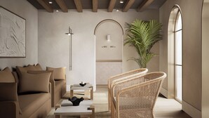 A modern interior with a sofa, a coffee table, a wicker chair, a potted plant, and a wall-mounted light fixture. - Casa Azure Member Of Meliá Collection (San Lawrenz)