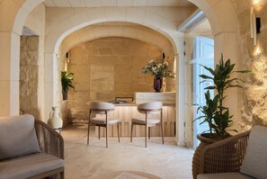 Un área de comedor con un arco de piedra, una mesa con sillas y plantas en macetas.