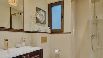 A bathroom with a large mirror, a sink, a toilet, and a shower.