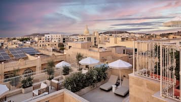A rooftop terrace with lounge chairs, umbrellas, and solar panels.