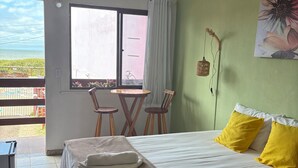 A hotel room with a bed, a table with chairs, a window with curtains, and a view of the outdoors.