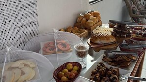 A buffet with various food items, including fruits, pastries, and meats, arranged on a table with a view of the outdoors.