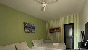 A hotel room with two beds, a ceiling fan, a painting, a television, and a door. - Pequena Sereia Guriri (São Mateus)