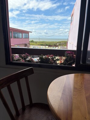 Une vue par la fenêtre sur un bâtiment, une chaise et une table.