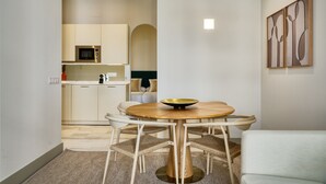 A modern kitchen with white cabinets, a microwave, and a dining area with a round wooden table and wicker chairs. - Luis de Vargas 2B by Home at Homes (Seville)