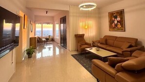 A spacious living room with a large flat-screen TV, a sofa, a coffee table, and a painting on the wall. - Villa Duka (Kruje)