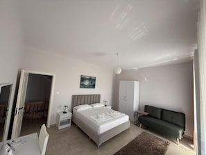 A modern bedroom with a bed, bedside table, nightstand, and a green sofa.