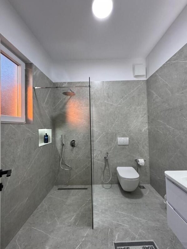 Ein modernes Badezimmer mit Duschkabine aus Glas, Toilette und Waschbecken.