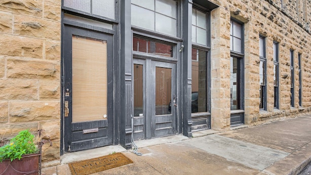 A stone building with large windows and a metal door.