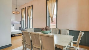 A dining area with a wooden table, chairs, a chandelier, and a bowl of decorative items on the table.